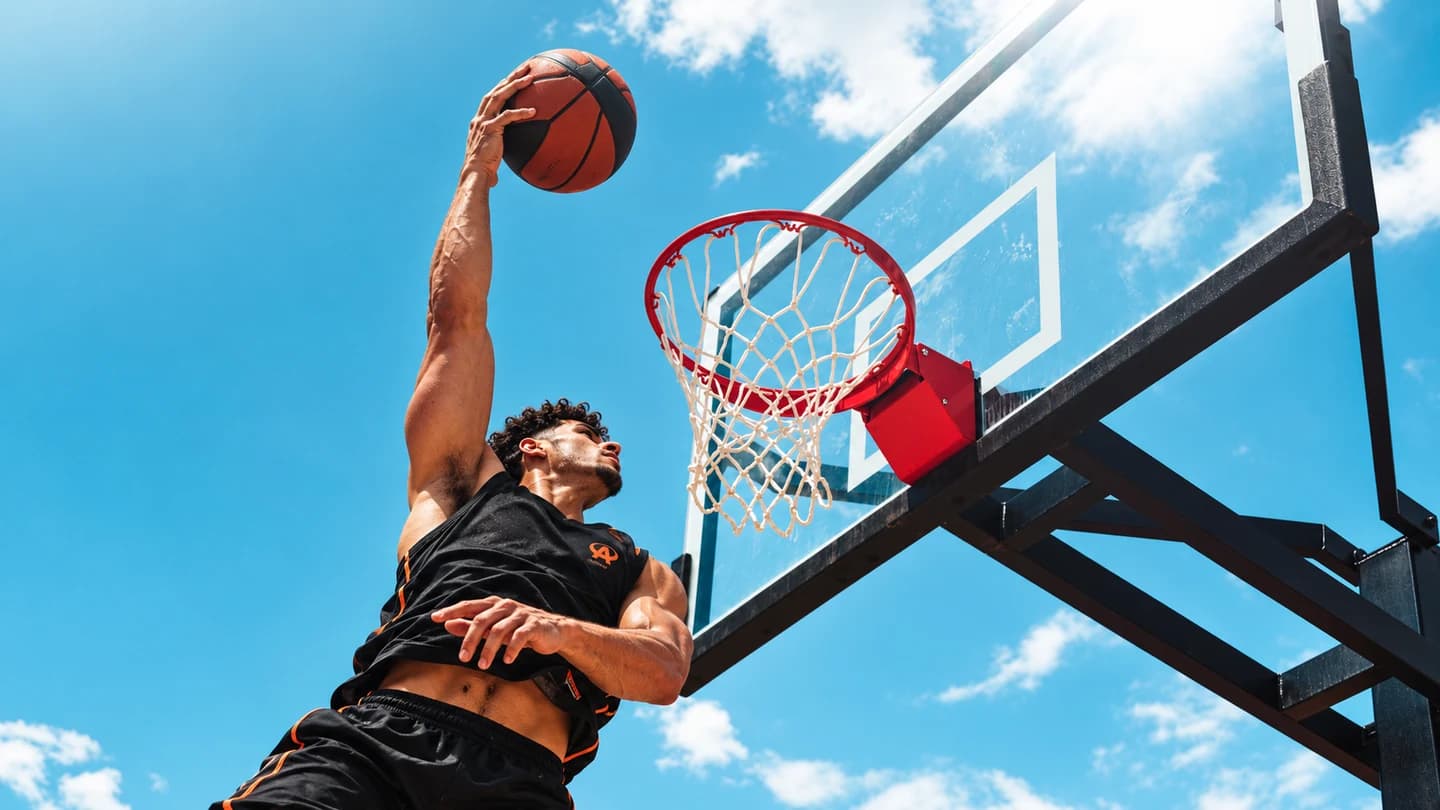 Joueur Athlete montant au dunk sur un terrain de basketball extérieur