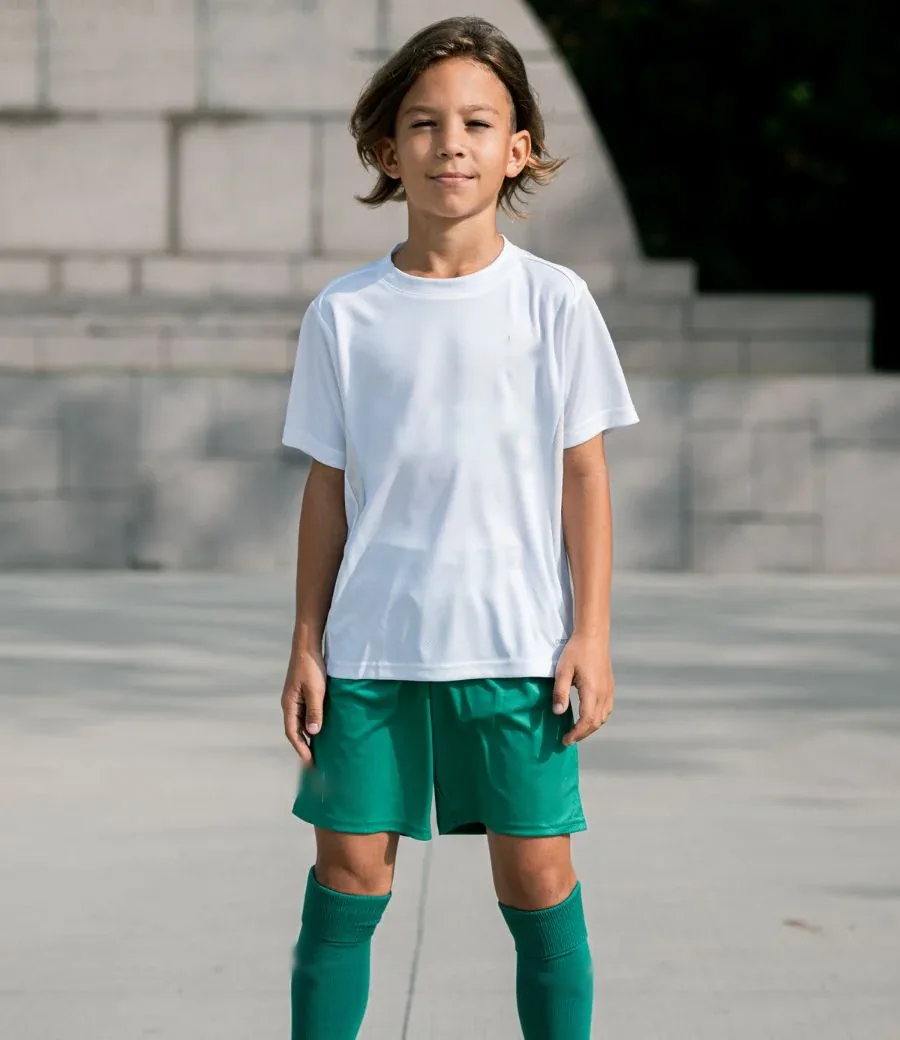 Jeune joueur d'académie en tenue de match blanche et verte, short et chaussettes assortis